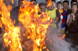 Tibetan exiles pray next to the burning funeral pyre of 27-year-old Jamphel Yeshi, who passed away Wednesday morning two days after he immolated himself in New Delhi, in Dharmsala, India, Friday, March 30, 2012. Buddhist monks chanted prayers and thousands of Tibetan exiles paid homage Yeshi, who burned himself alive as an act of protest against the visit by China's president, during a special ceremony in Dharmsala. (AP Photo/ Ashwini Bhatia)